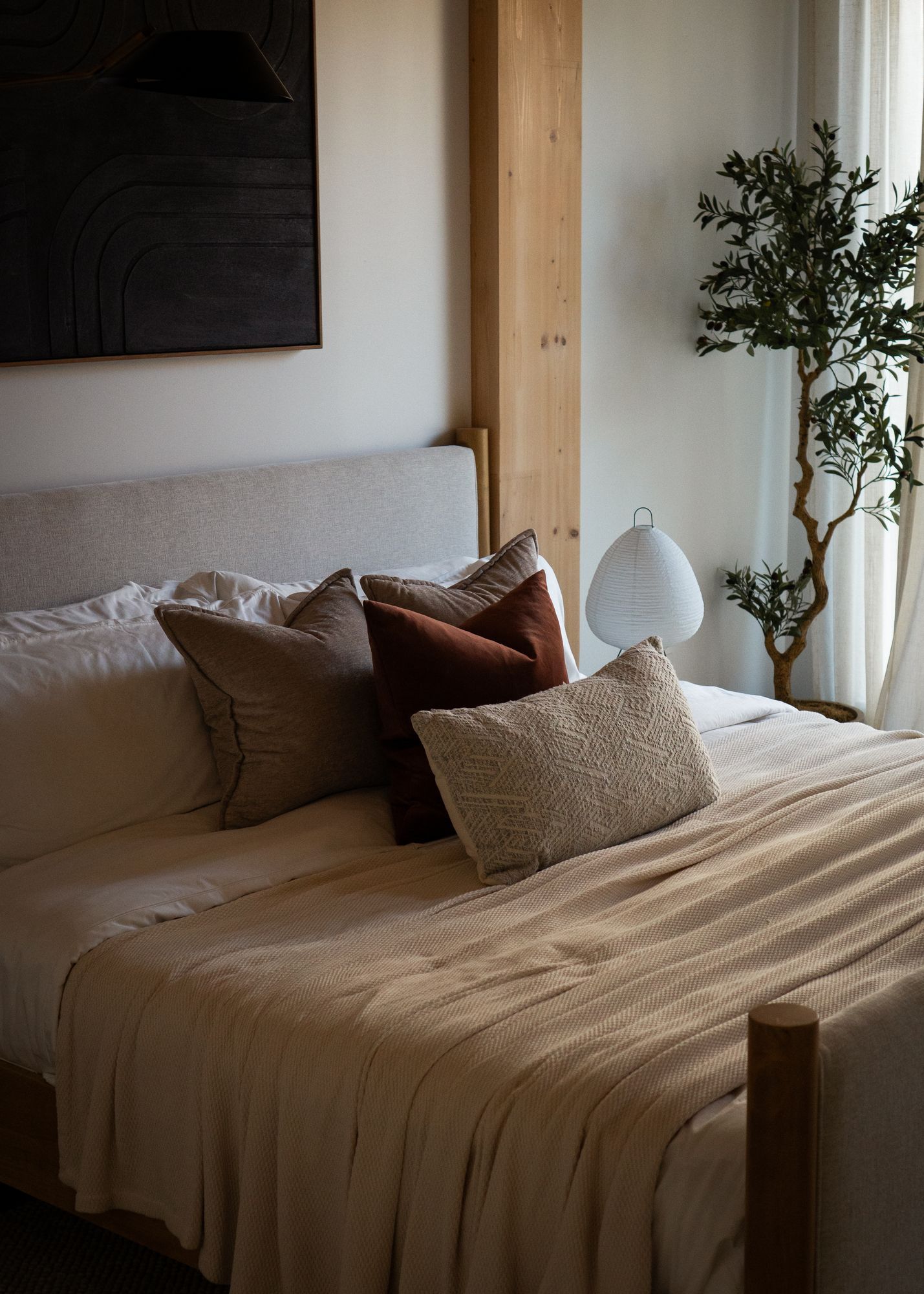 Bedroom with linen bedding and an olive tree by the window at 179 North 10th Street, Williamsburg, staged by Stage One