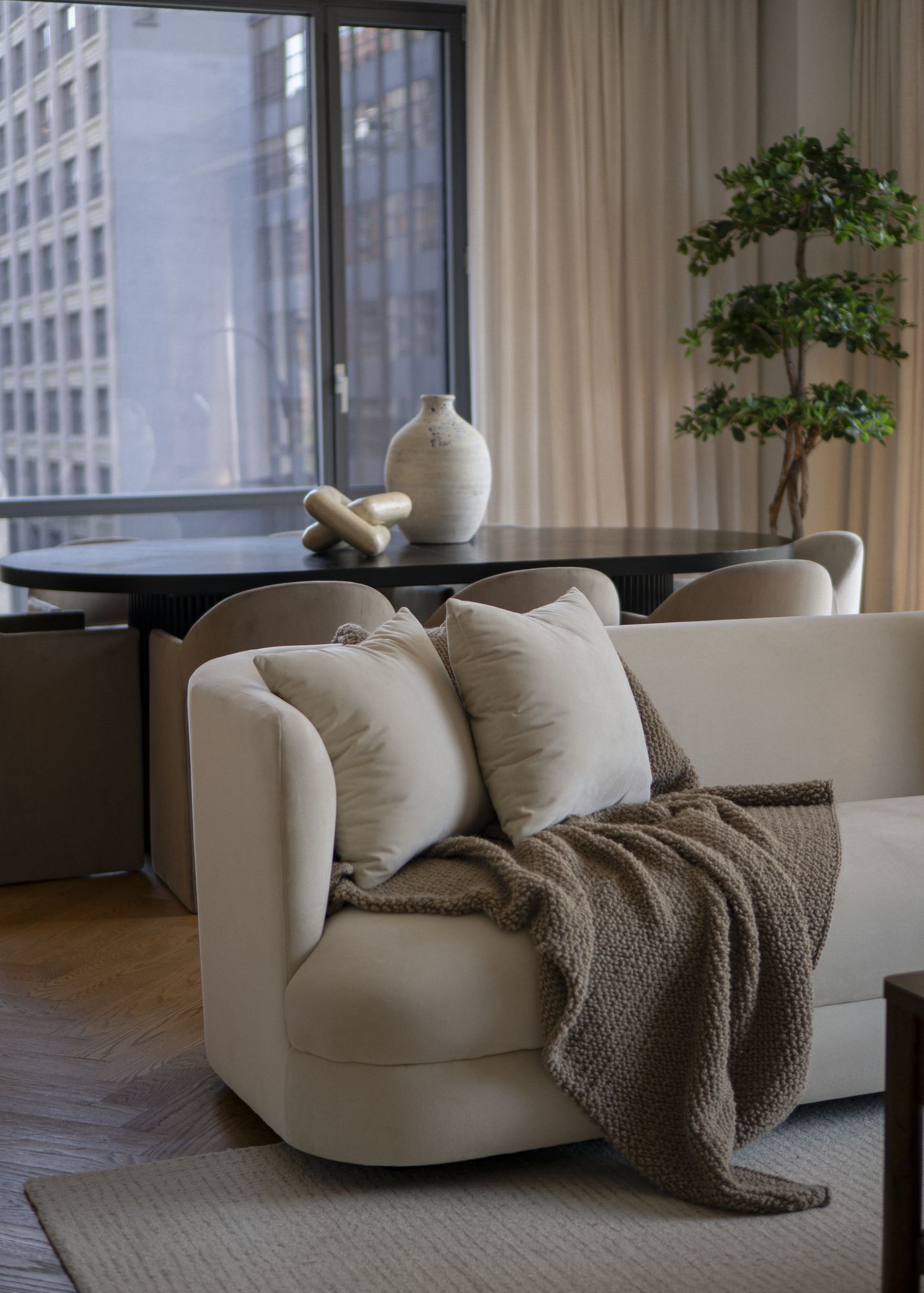 Living room sofa with a wool throw beside the dining table at 50 Madison Avenue, NoMad, staged by Stage One